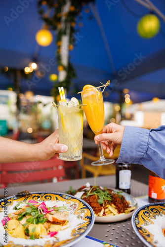 Friends toasting with cocktails in outdoor restaurant
People clinking summer drinks during dinner
Cheers with Aperol Spritz and mojito on terrace