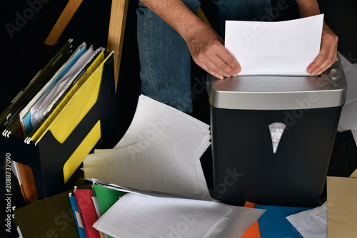 Photos High angle shot showing person feeding white paper into black shredder surrounde