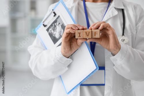 Female fertility doctor with abbreviation IVF and sonogram image in clinic, c...