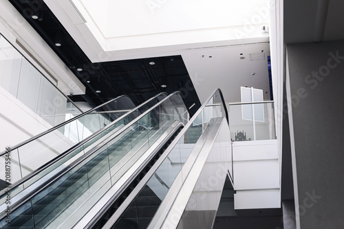 Modern empty shopping mall interior with escalators and contemporary architecture. Quiet retail space without customers. Commercial property. Consumer economy and urban lifestyle..