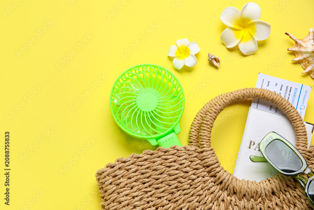 Obraz premium Bag with female summer accessories, passport, ticket and mini fan on yellow background with space for text