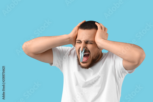 Canvastavla Stressed young man with clothespin on blue background