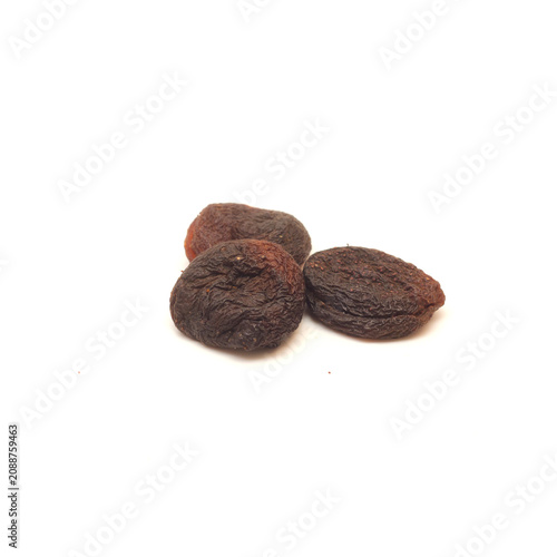 Three black dried apricots isolated on white background.