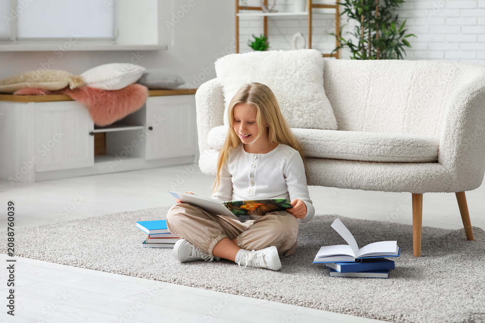 Obraz premium Little girl reading book on floor at home