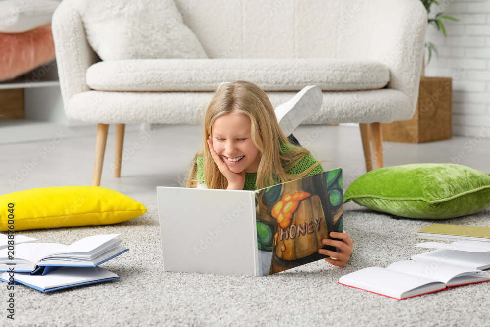 Obraz premium Happy little girl reading book on floor at home