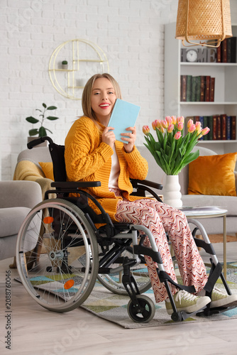 Young woman in wheelchair with book at home. International Womens Day