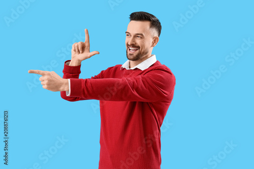 Fotografie Handsome man showing loser gesture on blue background