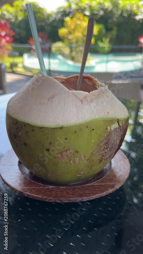 Enjoying Fresh Coconut Drink by a Sunny Outdoor Space