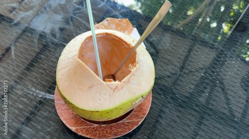 Opening a fresh coconut and drinking coconut water in a sunny outdoor setting