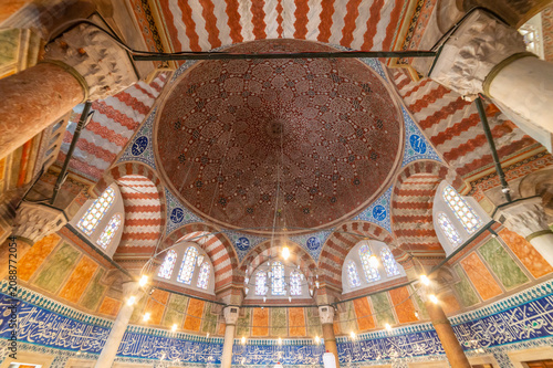 horizontal photo of the interior of a ottoman tomb with a big and colorful dome.