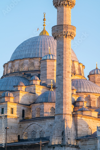 Vertical photo of an ottoman mosque facade with ther domes and minaret.