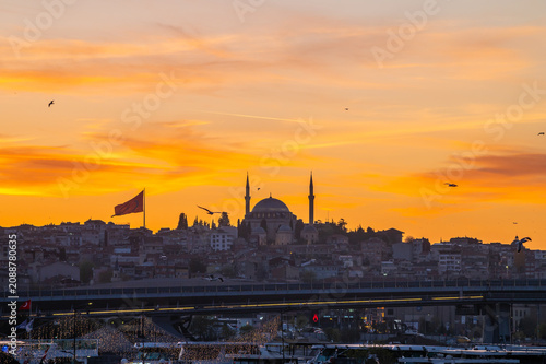 horizontal photo of a city landscape with silhouettes of a mosque in the center and other buildings in the sunset of istanbul.