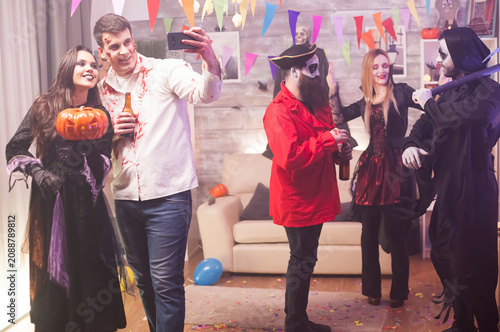 Cuadro en lienzo Smiling zombie and witch take a selfie together while celebrating Halloween, showing a playful costume party moment, adding festive character styling, dress-up atmosphere and seasonal party mood