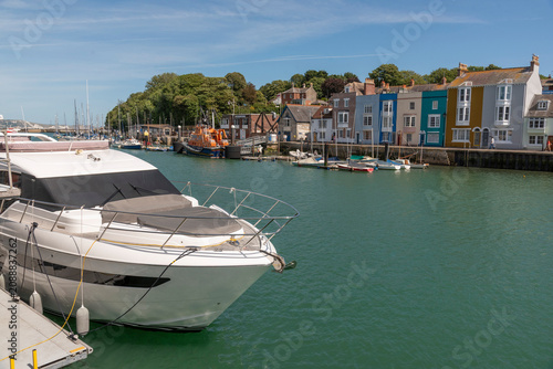 Weymouth Dorset England UK. 02.07.2026. A serene harbor scene unfolds with a luxury yacht in the foreground and a row of vibrant, historic buildings lining the waterfront