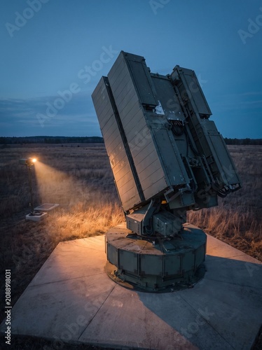 Advanced radar system or sensor array operating in a field at twilight, with a distant light source.