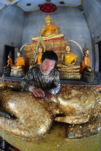 Thai Buddhists are applying gold leaf to