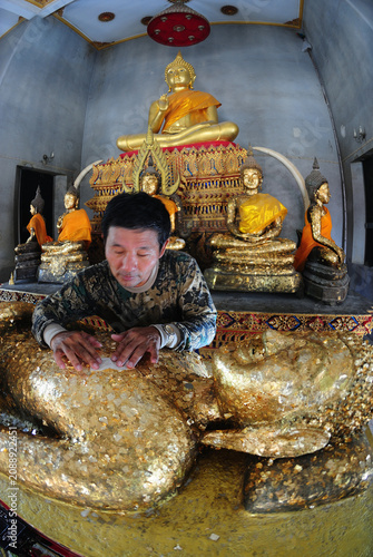 Thai Buddhists are applying gold leaf to