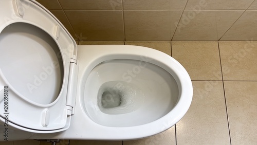 Modern White Ceramic Toilet with Open Lid Inside Clean Tiled Bathroom Captured from High Angle Perspective