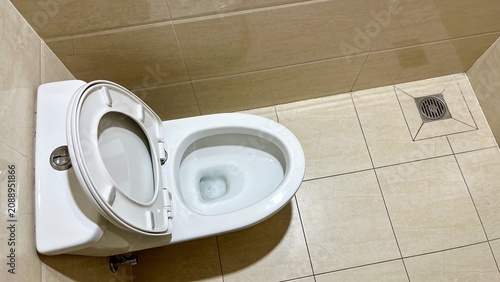 Modern White Ceramic Toilet with Open Lid Inside Clean Tiled Bathroom Captured from High Angle Perspective