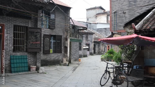 Authentic daily life scene in an old traditional Chinese town or village with buildings and country houses and a local dog wandering through the alleyway in regional Guangxi, China. 广西怀远