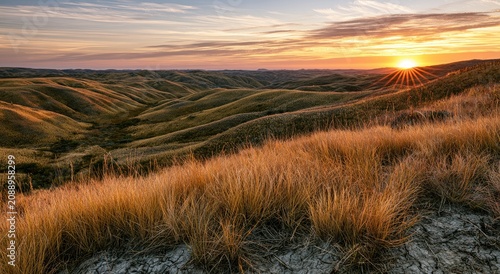 Golden sunbeams illuminate rolling hills and dry grass at sunset