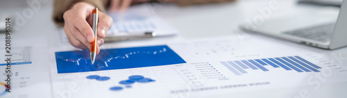 Business person analyzing financial documents and charts on desk in office