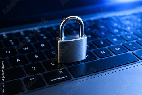 A silver padlock sits on a laptop keyboard, symbolizing security and protection online.
