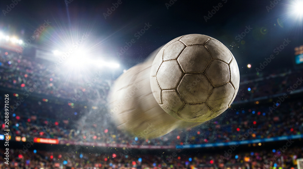 Fototapeta premium Soccer ball in motion during night match at stadium