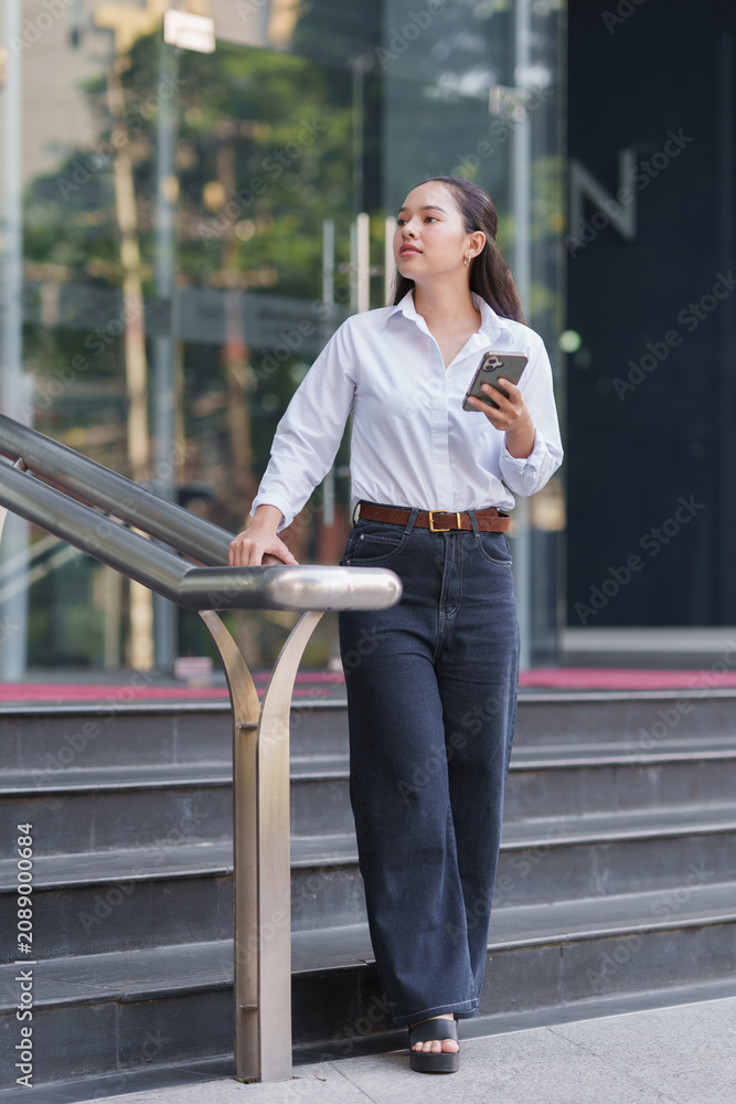 Fototapeta premium Woman standing on urban staircase using phone