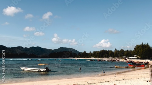 Obraz na plátně Idyllic tropical beach with anchored boats, clear blue water, sandy shore, and l