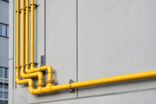 Yellow Industrial Pipes Mounted on Concrete Wall