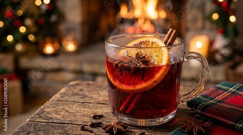 Warm mulled wine with orange and cinnamon by a cozy fireplace during Christmas.