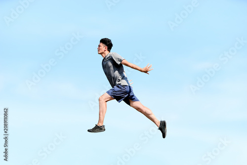 Quadro su tela 青空を背景に空中でダイナミックにジャンプする躍動感あふれる20代から30代の男性の横向きの全身写真