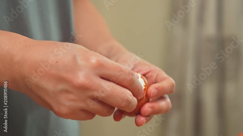 Woman’s hands peeling boiled egg in kitchen.