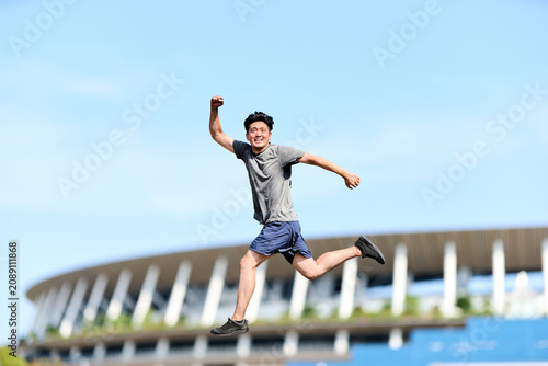 Fotografie 屋外で空中へジャンプしチャレンジ精神や挑戦や可能性をイメージするスポーツウェア姿のアクティブな男性