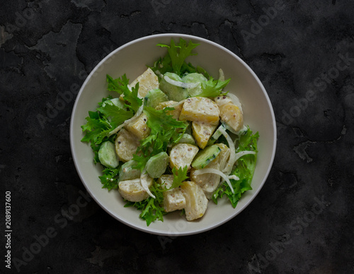 Cuadro en lienzo Potato salad with cucumbers and yogurt-mustard dressing on a dark background, to
