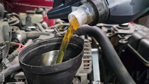 How to change engine oil in a car using a funnel in a garage