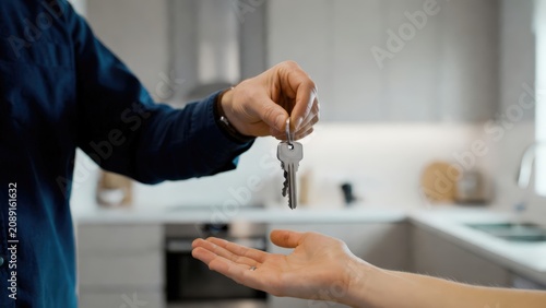 Handover of house keys as a visual concept for real estate marketing, property transaction services, mortgage advertising and rental business solutions.
