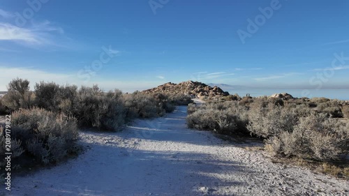 First-person point of view walking footage on a dirt hiking path surrounded by desert sagebrush. Scenic view of Antelope Island State Park, Great Salt Lake, Utah.