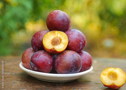 Cuadro en lienzo Fresh Red Plums on White Plate - Healthy Organic Stone Fruit with Golden Flesh