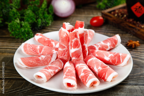Raw Marbled Beef Slices Arranged on Plate for Hot Pot Cooking with Fresh Ingredients