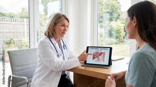 Doctor Explaining Treatment Pathway to Female Patient on Digital Tablet