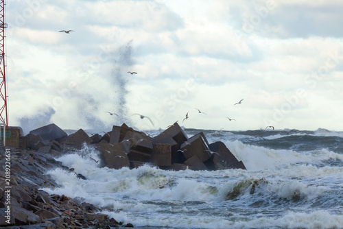 Storm waves crashing on rocky coastal breakwater