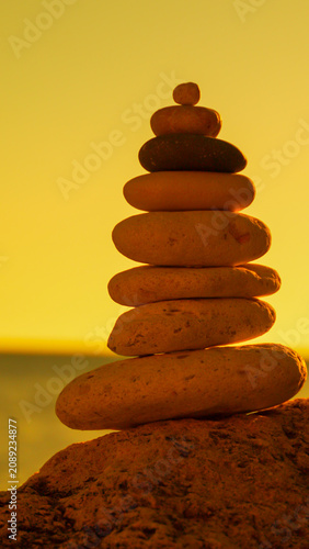 Stones balance sunset A stack of rocks on a beach at golden hour symbolizing peace and tranquility.
