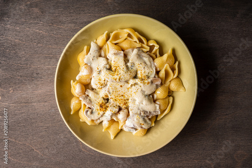 Homemade pasta with creamy mushroom sauce on dark wooden background. Shot from above.