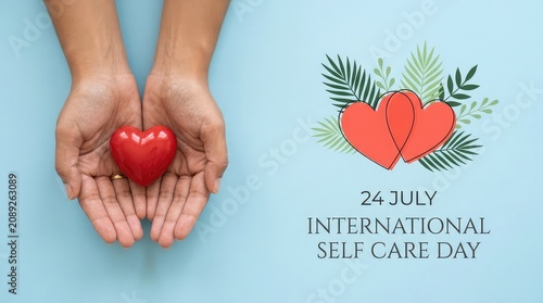 Hands holding a red heart shape graphic for International Self Care Day on bright turquoise background