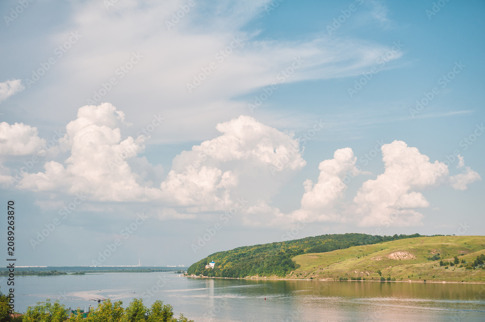Naklejka premium Scenic river reflects cloudy sky. Peaceful landscape invites travel