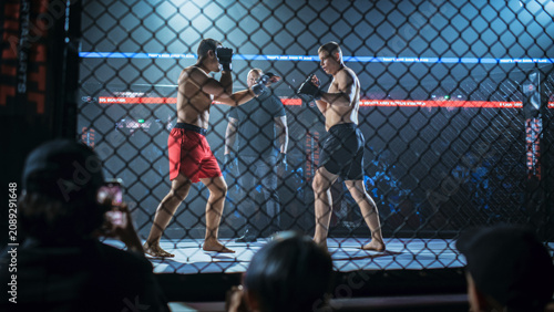 Fotografie Two Fighters Circle and Probe in an MMA Bout Inside the Cage, Referee Monitors Closely