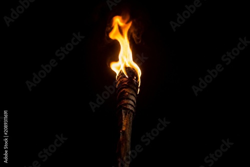 A single burning torch creating a focal point of light in darkness.