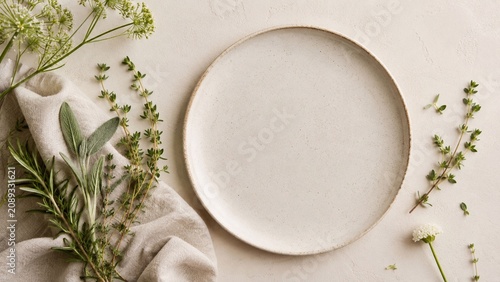 Minimal Ceramic Plate With Fresh Green Herbs Neutral flat lay of a blank ceramic plate on soft linen with fresh herbs, ideal for natural food styling background